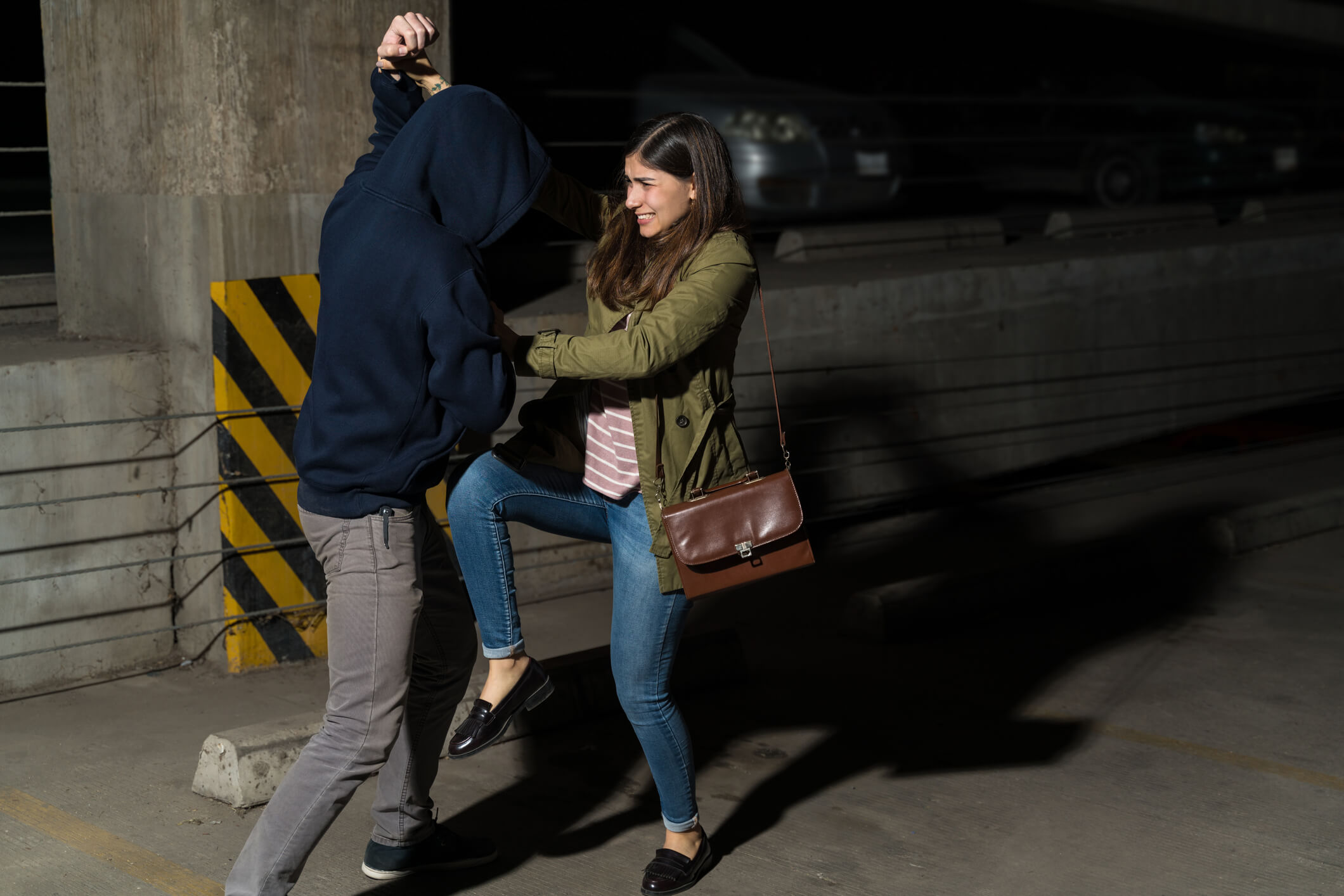 Young Hispanic woman defending herself from attacking thief in alley