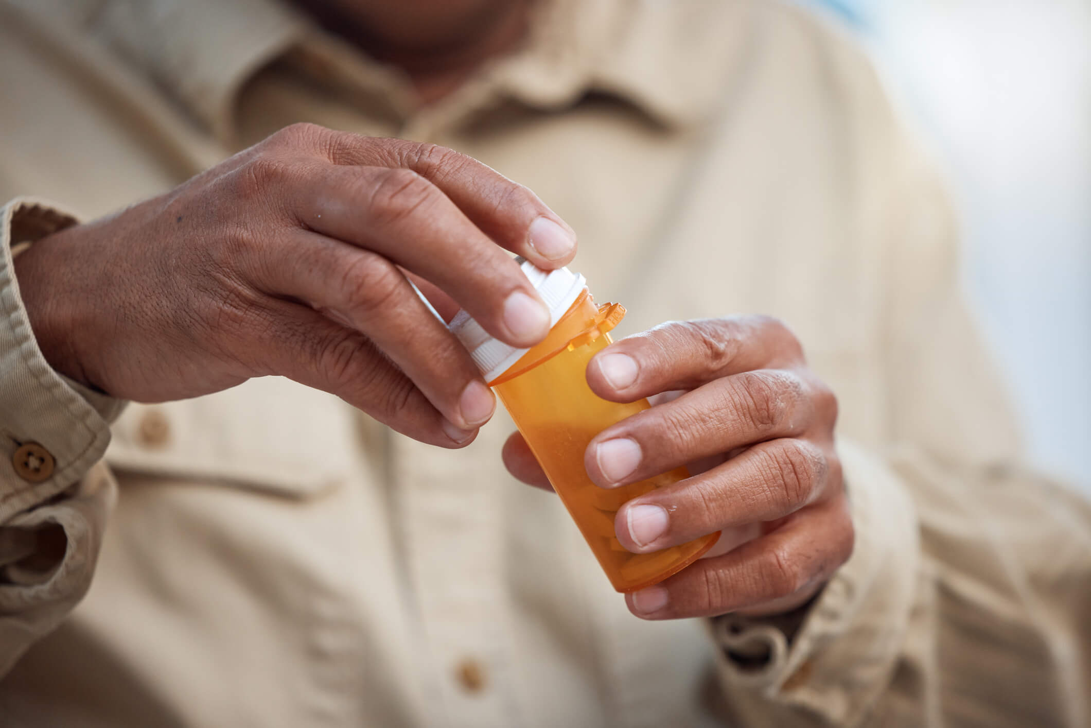 Close up of man holding an orange prescription drug bottle