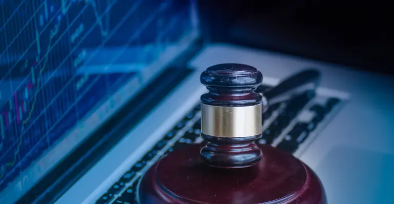 Judges gavel on keyboard with glowing computer screen monitor background