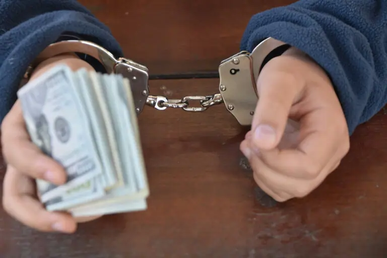 Man in handcuffs with cash in one hand
